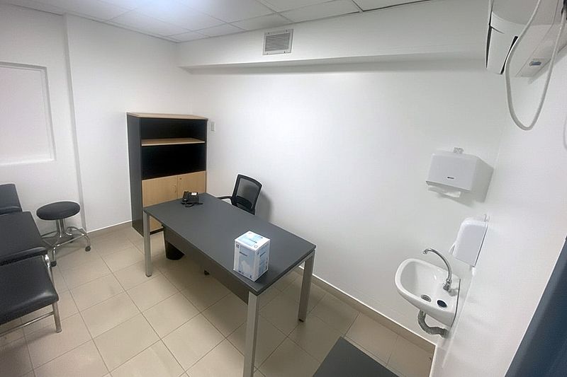 Consultorio equipado con escritorio, sillas y lavatorio